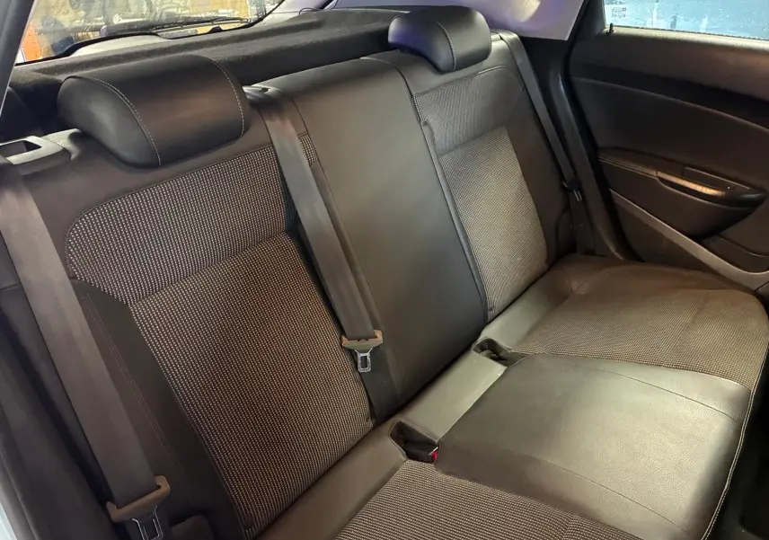 Vue intérieure de la banquette arrière en tissu et cuir noir de l’Opel Astra 1.6 CDTI gris, avec ceintures de sécurité visibles.