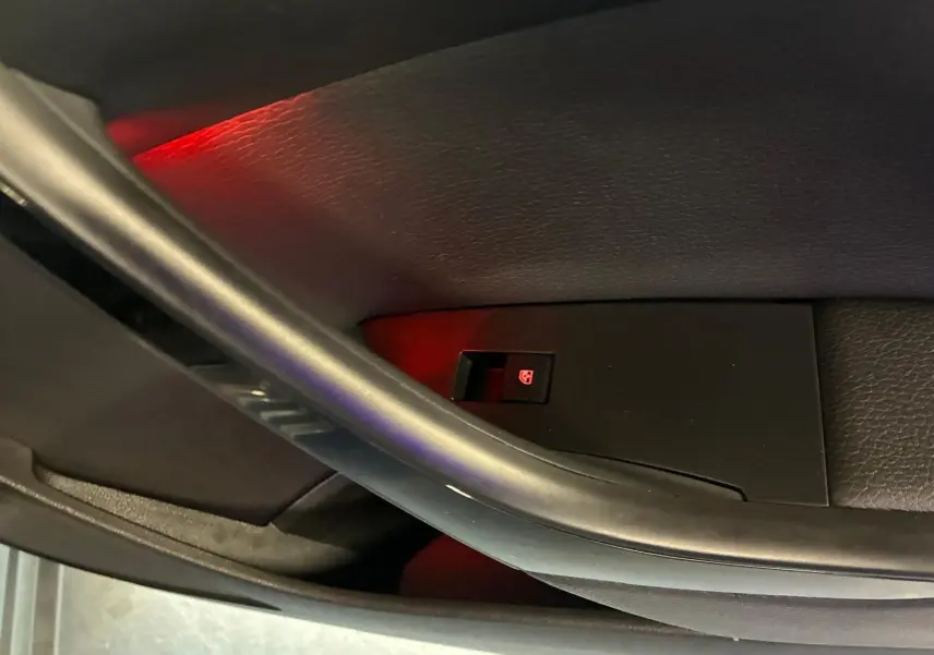 Détail de la commande de lève-vitre électrique sur la porte intérieure côté conducteur d'une Opel Astra gris 2015.