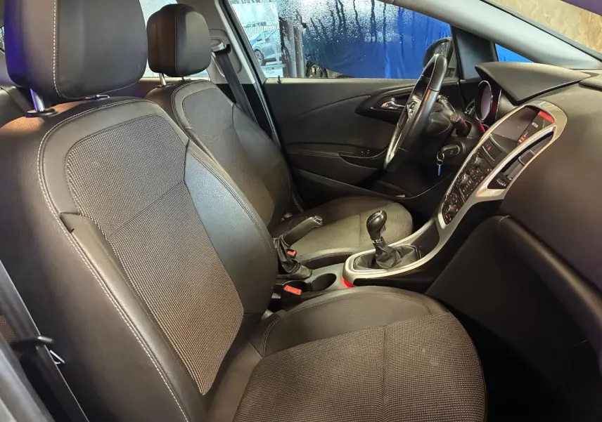 Intérieur avant droit de l’Opel Astra gris 2015, montrant les sièges, volant et console centrale avec boîte manuelle.