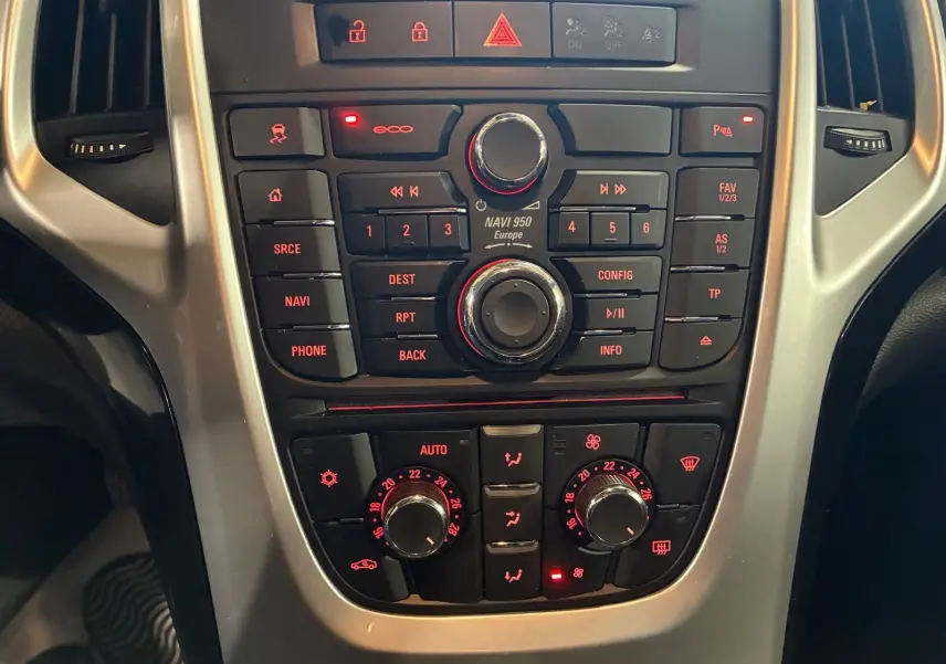 Vue rapprochée du tableau de bord de l'Opel Astra 1.6 CDTI 110 gris, avec commandes de navigation et climatisation éclairées.