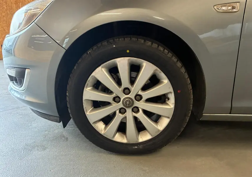Gros plan sur la roue avant gauche d'une Opel Astra gris métallisé de 2015 avec jante alliage et clignotant latéral.