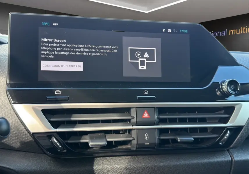 Vue rapprochée du tableau de bord central tactile noir et argenté de la Citroën C4 hybride 2025, avec écran multifonctions allumé.