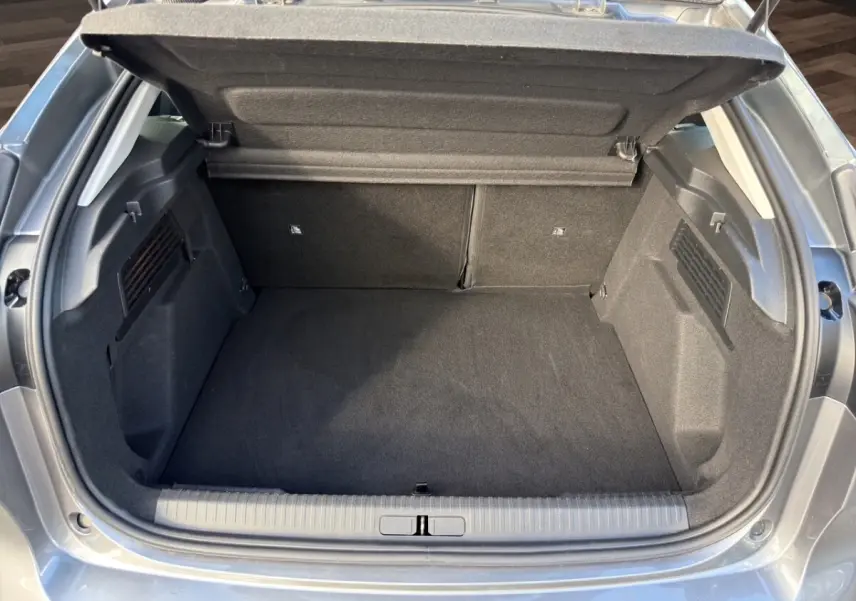 Coffre ouvert vu de l'arrière d'une Citroën C4 hybride gris foncé, espace de chargement propre et spacieux.