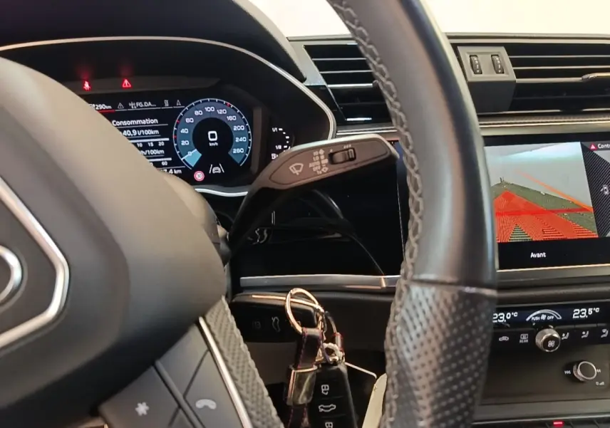 Vue intérieure centrée sur le volant cuir et le tableau de bord digital de l'Audi Q3 Sportback 2024 hybride rechargeable.