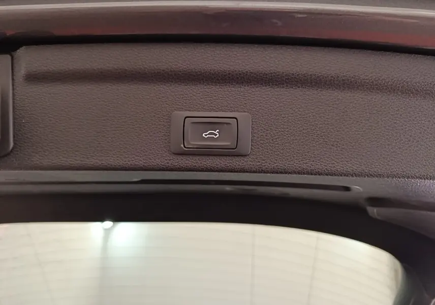 Bouton d'ouverture électrique du coffre sur le hayon intérieur d'un Audi Q3 Sportback gris clair 2024.
