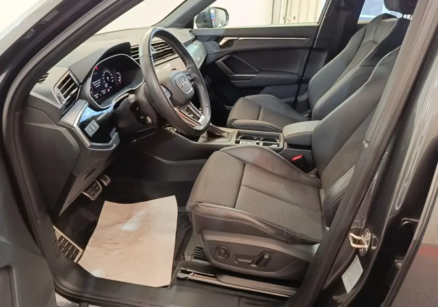 Intérieur côté conducteur de l’Audi Q3 Sportback gris clair 2024, avec sièges en tissu et tableau de bord digital.