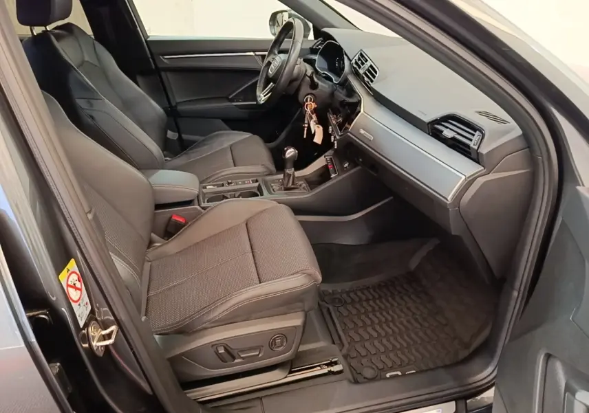 Vue intérieure côté conducteur de l'Audi Q3 Sportback gris clair 2024, avec sièges tissu et tableau de bord moderne.