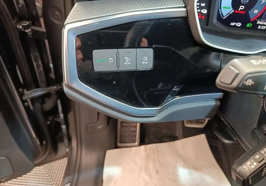 Détail du tableau de bord côté gauche de l’Audi Q3 Sportback 45 TFSI e 2024 avec commandes d’éclairage et affichage numérique.