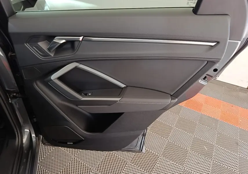 Vue intérieure de la porte arrière droite d’un Audi Q3 Sportback gris clair avec habillage noir et insert argenté.