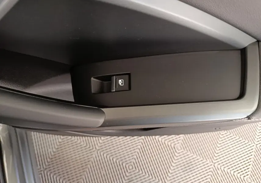 Détail de l'interrupteur de lève-vitre électrique sur la porte intérieure côté conducteur d'un Audi Q3 Sportback gris clair.