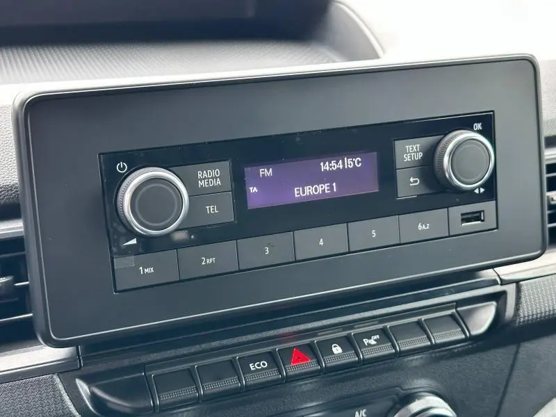 Écran multifonction noir affichant la radio Europe 1 dans l'habitacle du Nissan Townstar gris 2024.