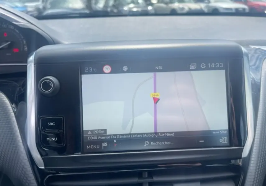 Écran tactile de navigation 3D au tableau de bord d'une Peugeot 208 blanche perle, vue intérieure frontale.