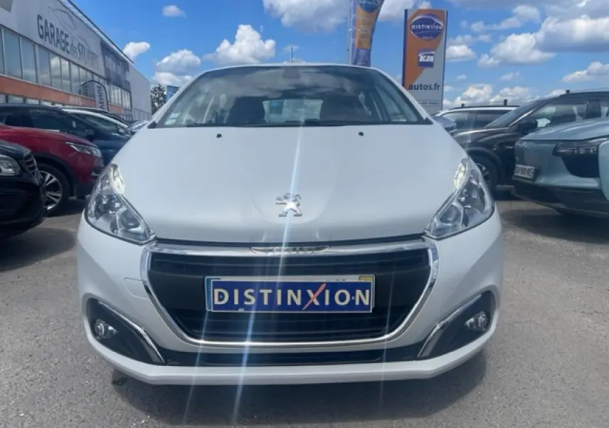 Peugeot 208 blanc perle vue de face, calandre noire avec contours chromés et logo lion au centre.