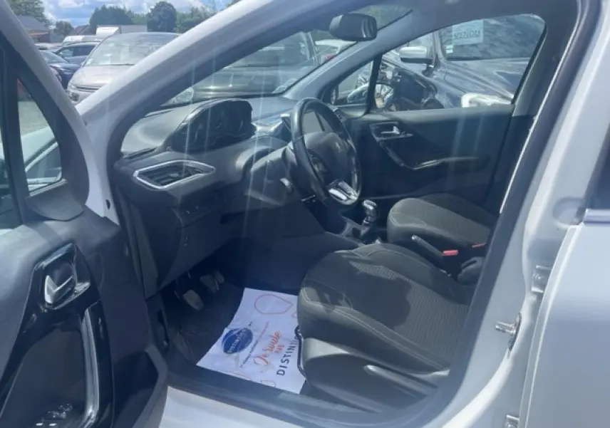 Intérieur de la Peugeot 208 blanc perle, vue côté conducteur avec volant multifonction et sièges noirs.