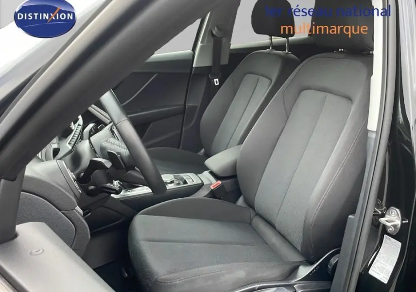 Vue intérieure côté conducteur de l'Audi Q2 35 TFSI S-Line 2023 avec sièges tissu noir et tableau de bord moderne.