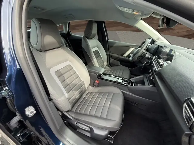 Vue intérieure côté conducteur de la Citroën C4 Hybride 2025 bleue, sièges avant gris avec tableau de bord moderne.