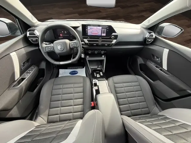 Vue intérieure avant de la Citroën C4 hybride 2025, tableau de bord avec écran tactile central et volant cuir multifonctions.