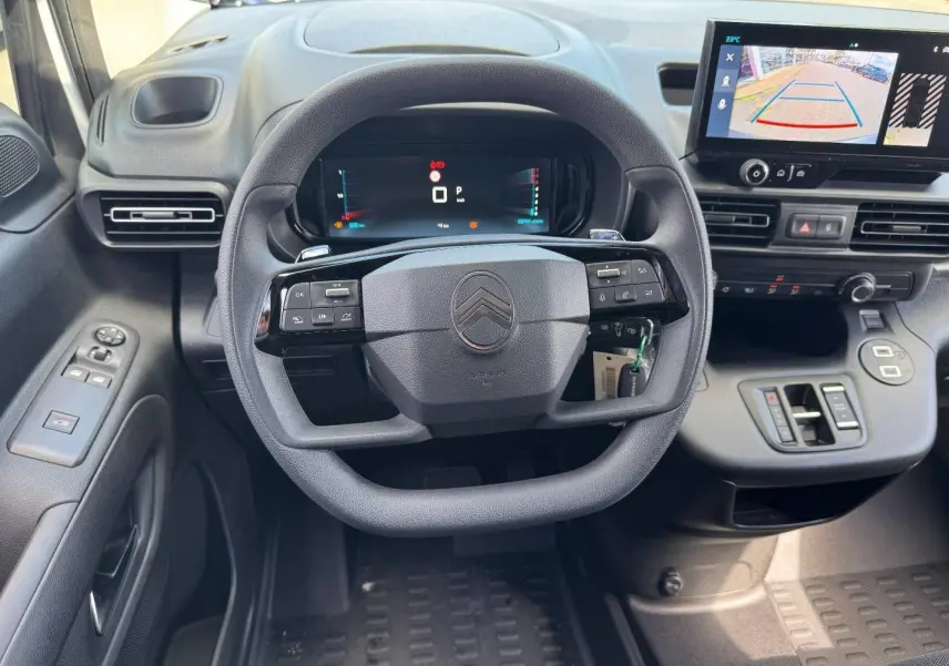 Vue intérieure centrée sur le volant multifonction et l'écran tactile affichant la caméra de recul du Citroën Berlingo XL blanc.