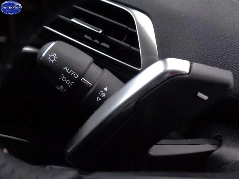 Gros plan sur la commande des phares et clignotants à gauche du volant dans l’habitacle noir du Peugeot 3008 Gris Artense.