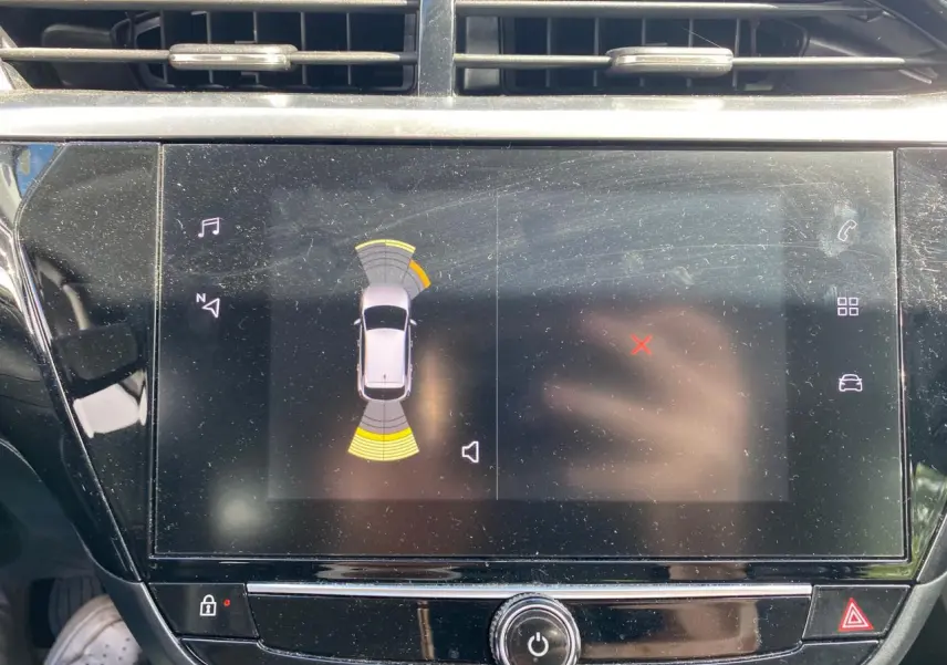 Écran tactile central de l'Opel Corsa bleu nautique 2021 affichant l'aide au stationnement avec capteurs actifs.