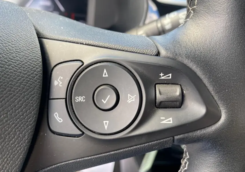 Gros plan sur les commandes audio au volant en cuir noir de l'Opel Corsa 1.2i Turbo 2021.