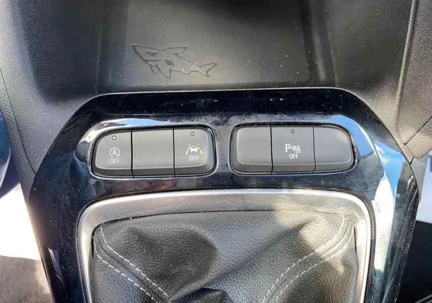 Gros plan sur la console centrale noire de l'Opel Corsa 1.2i Turbo 2021 avec boutons de contrôle et soufflet de levier de vitesse en cuir.