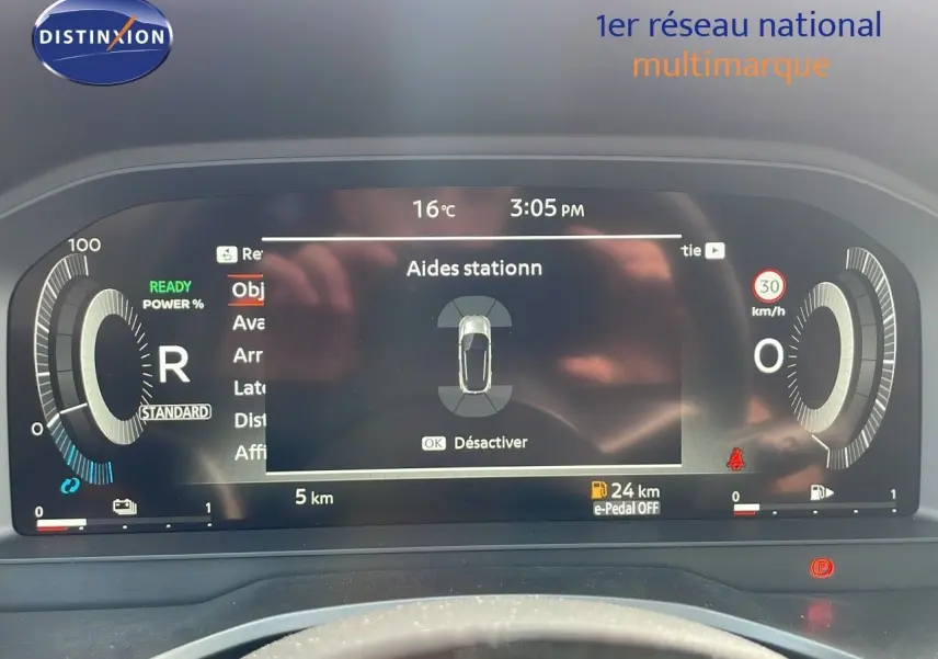 Tableau de bord numérique du Nissan Qashqai blanc nacré, affichant l'aide au stationnement et indicateurs de conduite.