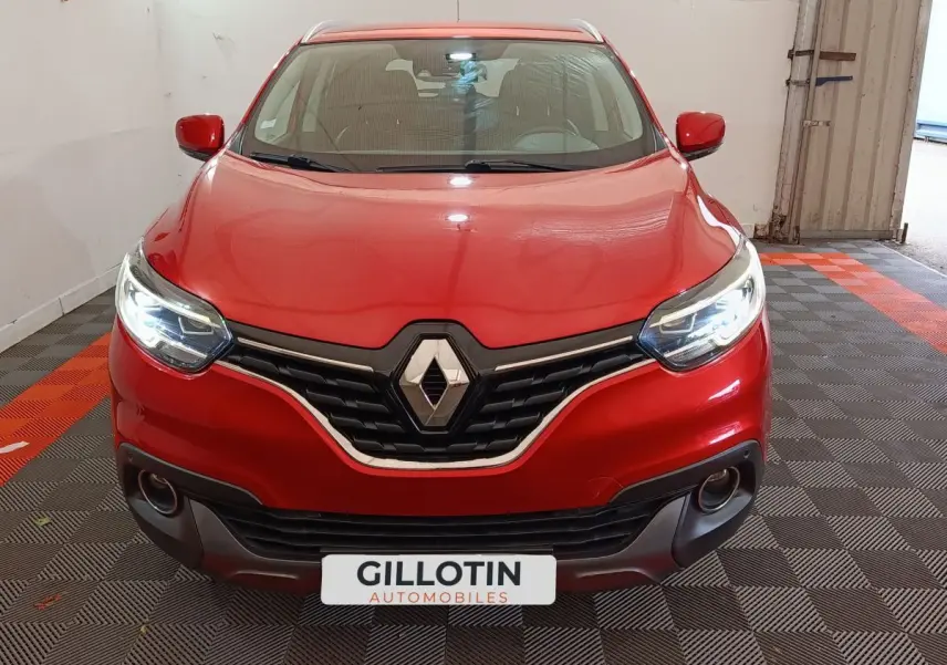 Vue avant d'un Renault Kadjar rouge avec phares LED allumés dans un garage au sol carrelé noir et orange.