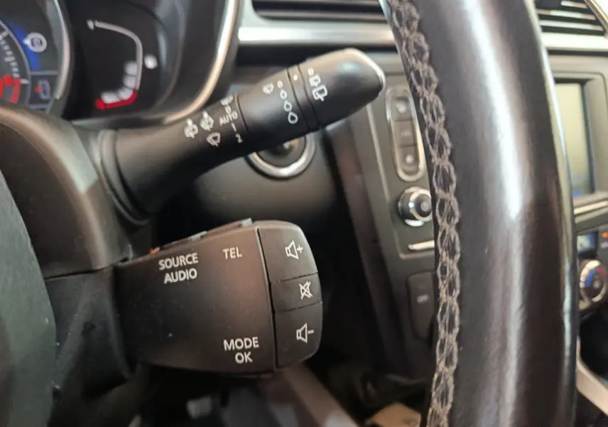 Gros plan sur les commandes audio et téléphone au volant cuir du Renault Kadjar Intens rouge, tableau de bord en arrière-plan.