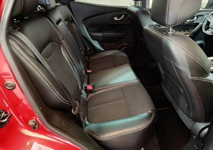 Vue intérieure côté arrière droit du Renault Kadjar Intens rouge, montrant les sièges en cuir noir avec surpiqûres blanches.