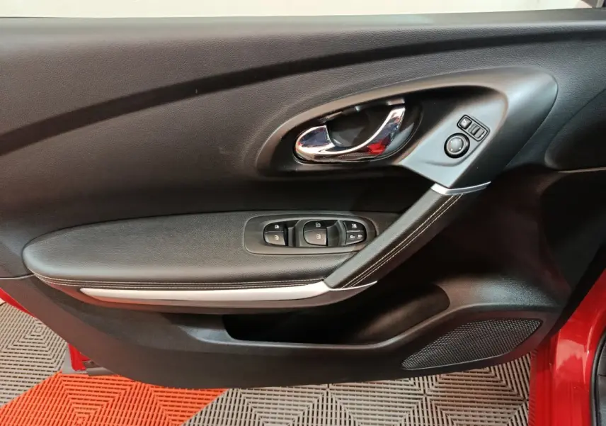 Poignée de porte intérieure côté gauche noire avec commandes électriques sur Renault Kadjar Intens rouge, vue rapprochée.