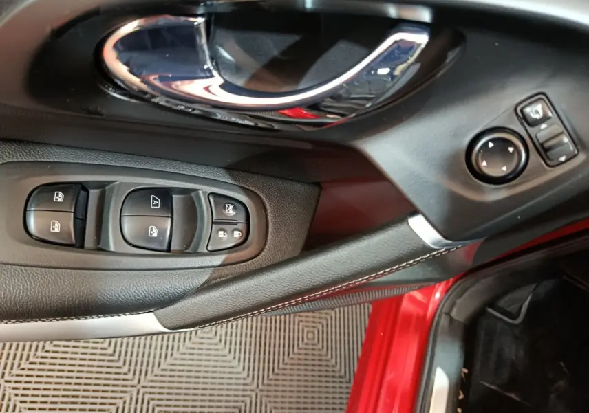 Gros plan sur la porte côté conducteur du Renault Kadjar rouge, montrant les commandes des vitres et rétroviseurs.