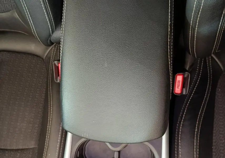 Vue plongeante sur la console centrale noire en cuir avec accoudoir et porte-gobelets du Renault Kadjar Intens rouge.