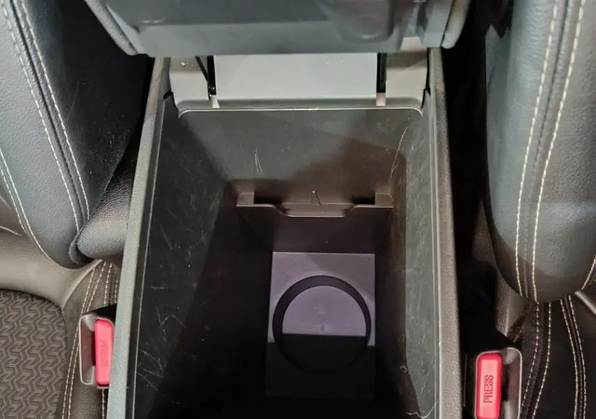 Vue plongeante sur la console centrale ouverte du Renault Kadjar Intens rouge, montrant le rangement intérieur et les ceintures de sécurité.