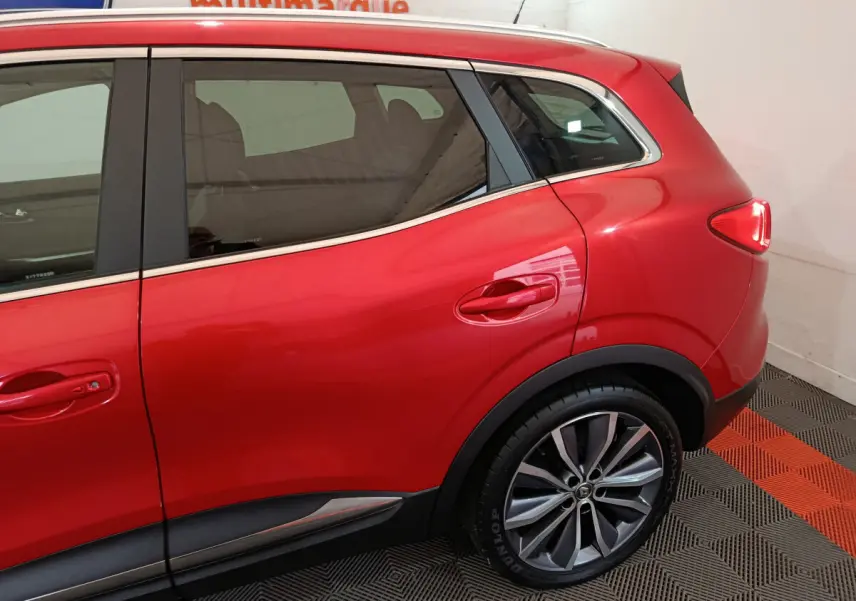 Vue latérale côté droit du Renault Kadjar rouge mettant en valeur la porte arrière et la roue arrière avec jante alliage.