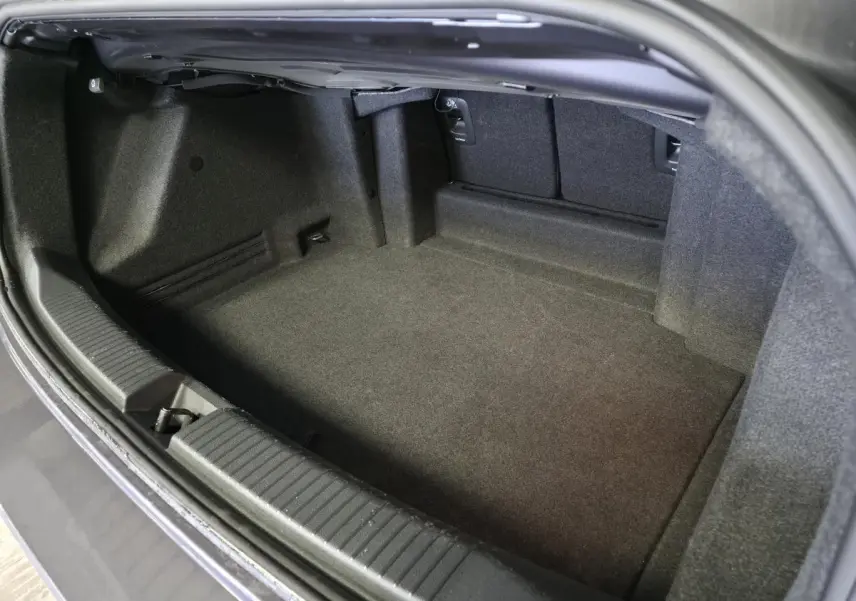 Coffre ouvert d'un Volkswagen T-Roc cabriolet gris 2024, montrant l'espace de rangement intérieur vide.