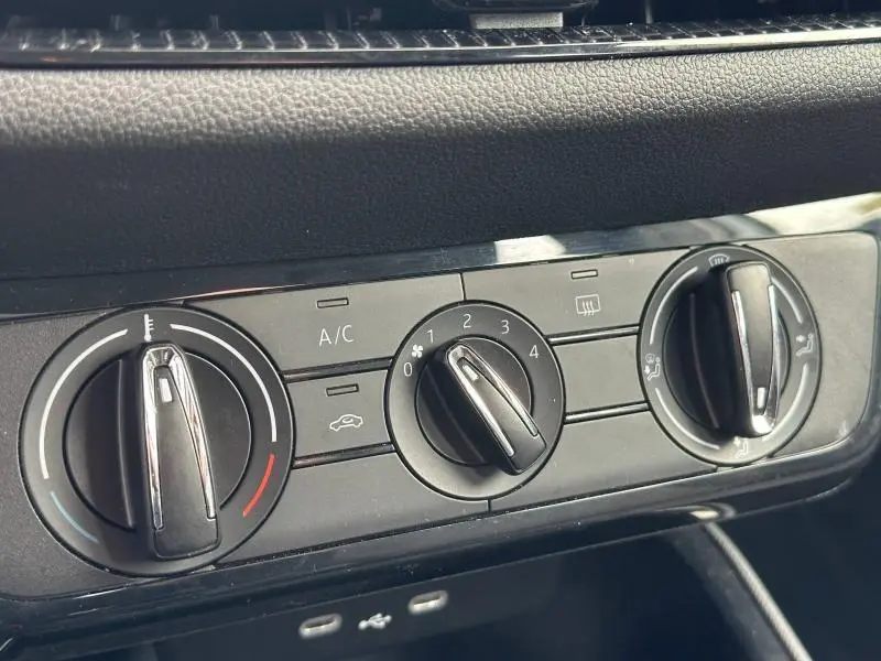 Gros plan sur les commandes de climatisation manuelle noires du tableau de bord d'une Skoda Fabia bleu 2024.