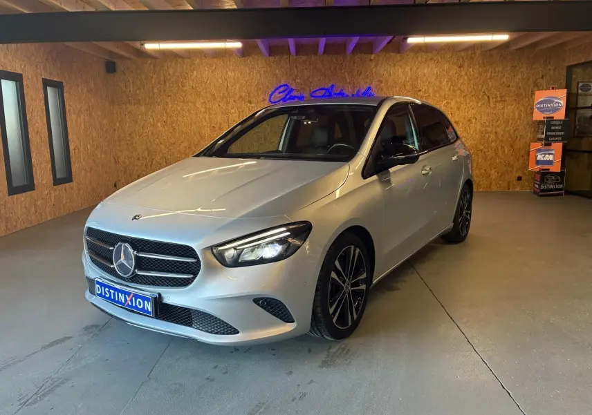 Vue 3/4 avant droite d'une Mercedes Classe B 200D Progressive Line gris métallisé avec jantes noires en intérieur showroom.