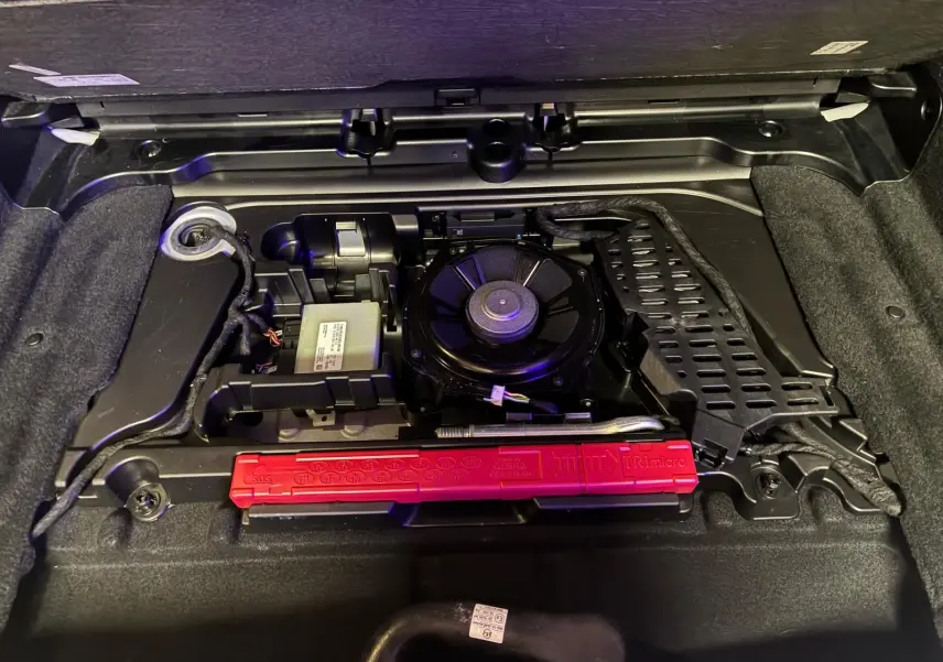 Vue rapprochée du compartiment de rangement sous le coffre d’une Mercedes Classe B 200D gris, montrant les outils et équipements d’origine.