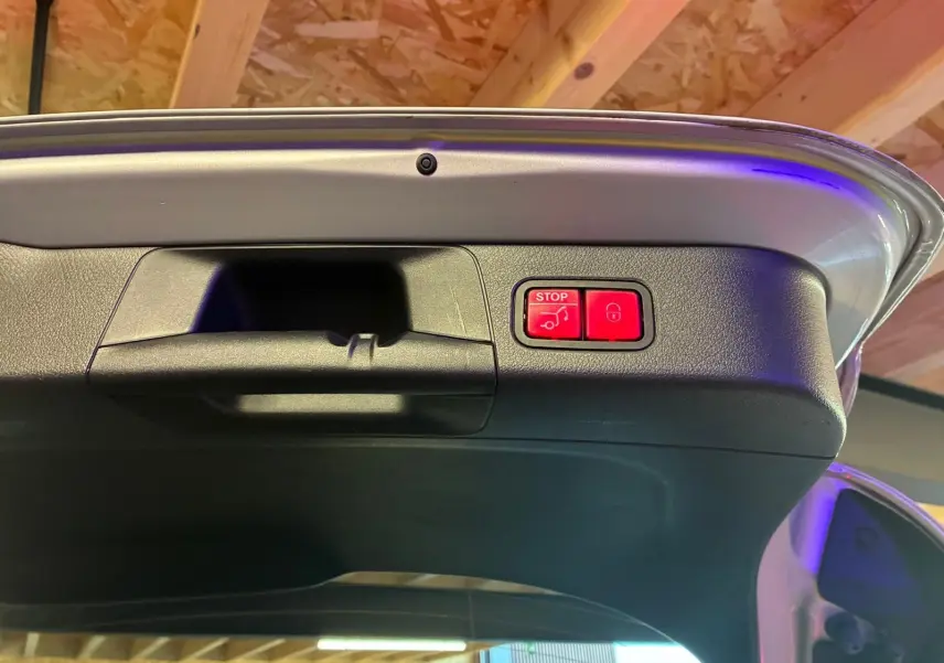 Bouton rouge d'ouverture et fermeture électrique du hayon sur le bord intérieur du coffre d'une Mercedes Classe B gris 2019.
