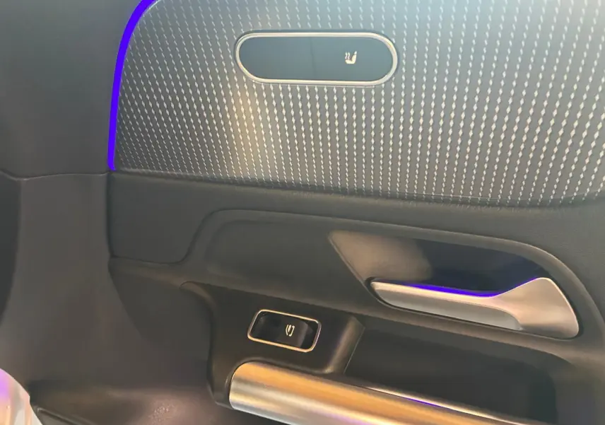 Détail de la porte côté gauche de la Mercedes Classe B 200D gris, avec éclairage d'ambiance violet et bouton de verrouillage.