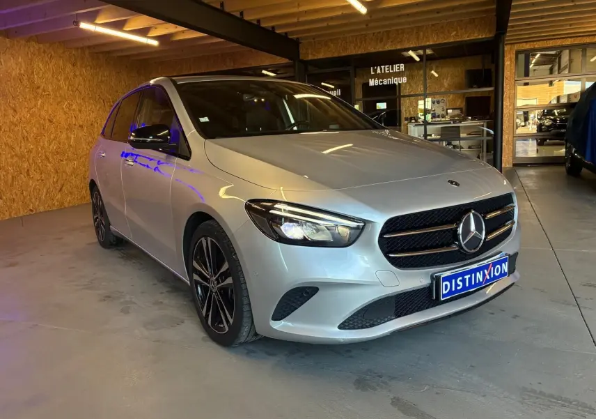 Mercedes Classe B 200D Progressive Line gris vue 3/4 avant droit dans un garage avec éclairage intérieur.