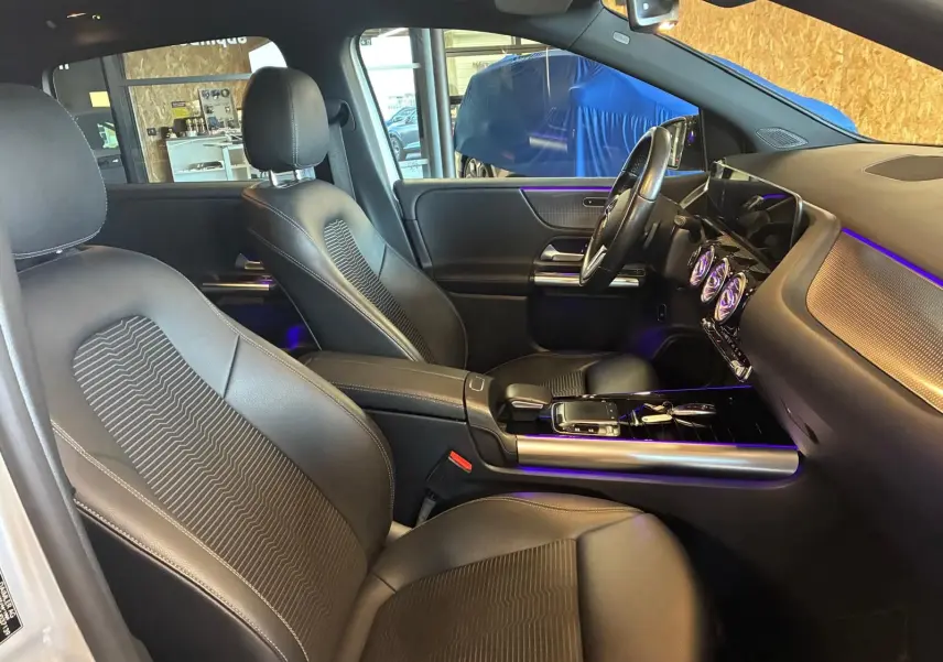 Vue intérieure côté droit de la Mercedes Classe B 200D Progressive Line 2019 avec sièges tissu gris et éclairage d’ambiance violet.