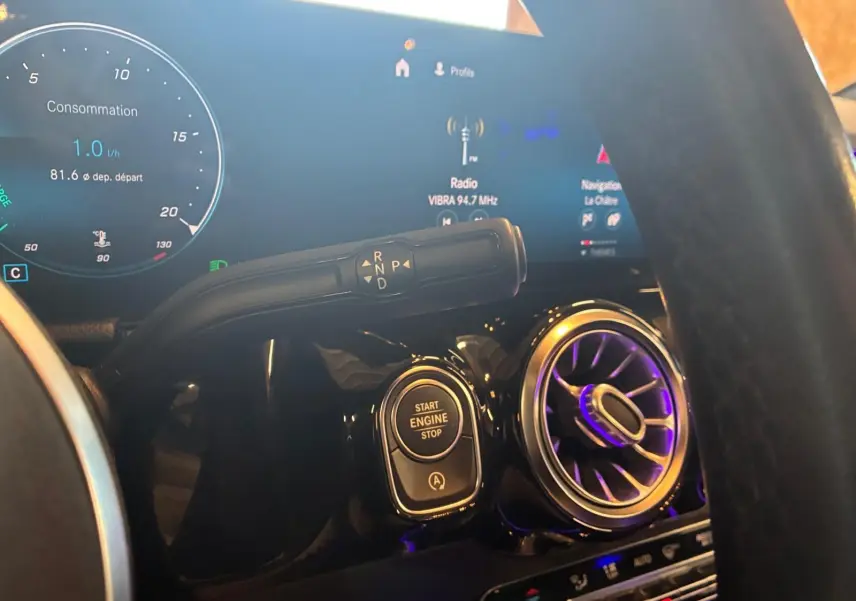 Gros plan intérieur sur la console centrale d'une Mercedes Classe B 200D grise, avec bouton start/stop et commandes de boîte auto.