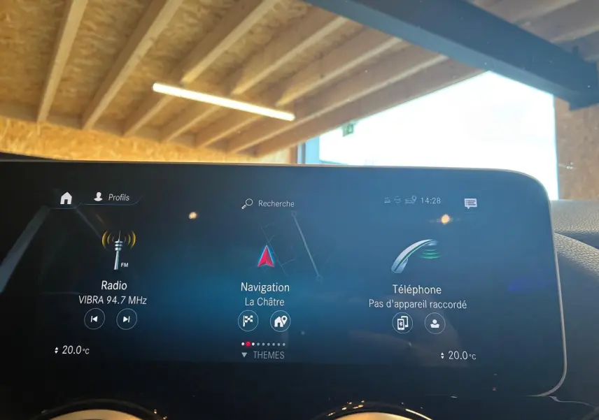 Écran central tactile de la Mercedes Classe B 200D gris, affichant radio, navigation et téléphone, intérieur sous lumière naturelle.