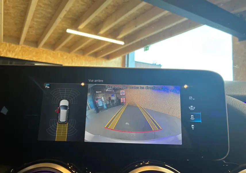 Écran intérieur de la Mercedes Classe B 200D montrant la caméra de recul avec guidage et capteurs de stationnement.
