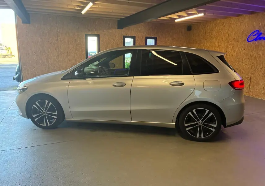 Vue de profil côté gauche d'une Mercedes Classe B 200D Progressive Line gris métallisé, avec jantes alliage noires et toit lisse.