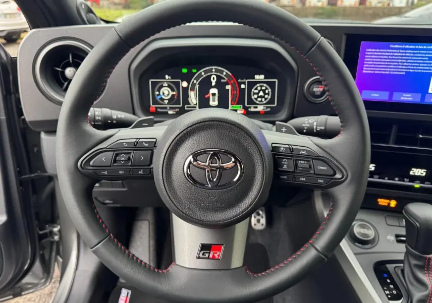 Vue rapprochée du volant noir avec surpiqûres rouges et logo GR de la Toyota Yaris GR Pack Techno.