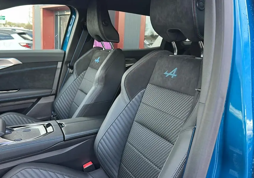Vue intérieure côté gauche des sièges avant en cuir et alcantara avec logo Alpine bleu sur Renault Austral bleu outremer 2026.