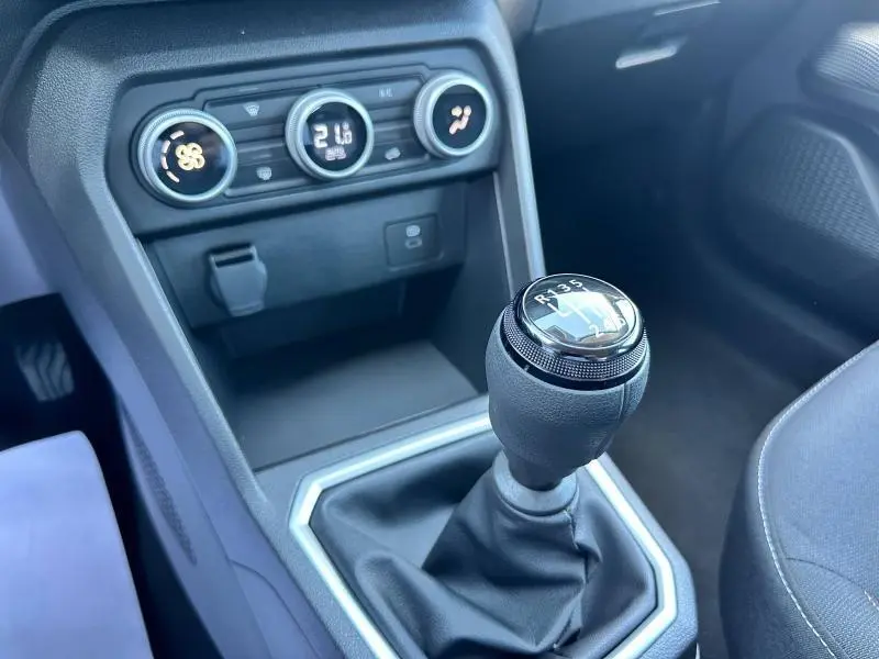 Le levier de vitesses manuel noir de la Dacia Sandero beige Safari vu côté droit avec commandes de climatisation au tableau de bord.